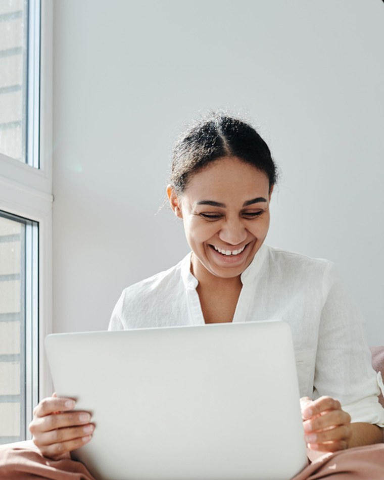 A woman working at a laptop, smiling